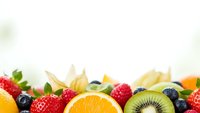 Fresh colorful fruit border with strawberries, orange, kiwi, blueberries and raspberries on white background for healthy eating and nutrition concepts.