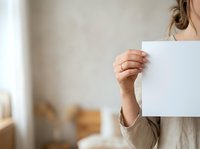 Close-up of a woman holding a blank white card or paper in her hand, suitable for mockups, advertising, promotions, and marketing campaigns.