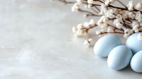 Pastel blue Easter eggs and delicate white spring blossoms on light background create serene seasonal composition for holiday celebrations and spring decor.
