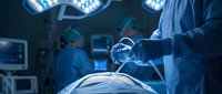 Surgeon performing minimally invasive laparoscopic surgery in modern operating room with advanced medical equipment and surgical lights overhead.