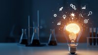 Glowing light bulb with innovation icons and laboratory glassware in background representing scientific research and creative breakthrough concepts.