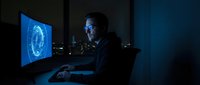 Cybersecurity expert analyzing digital fingerprint data on computer screen in dark office environment for network security and identity verification.