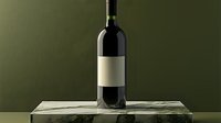 Dark wine bottle with blank label on marble surface against deep green background, dramatic lighting creates elegant mood for product photography and beverage marketing.