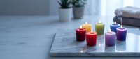 Colorful scented candles burning on marble surface creating cozy spa atmosphere for relaxation meditation and aromatherapy wellness rituals at home.