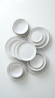 Overhead view of stacked white dinnerware with silver rims arranged on neutral background, showcasing tableware collection for dining and kitchen design projects.