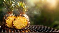 Fresh grilled pineapple slices on barbecue grill with rising smoke and warm sunset lighting, tropical summer fruit cooking outdoors.