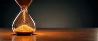 Golden sand flowing through hourglass on wooden surface against dark background symbolizing time passage, deadlines, and life moments in business concept.