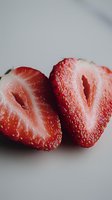 Fresh cut strawberry halves showing vibrant red flesh and natural texture on white background, macro close-up view highlighting juicy details and seeds.
