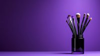 Professional makeup brushes set in black holder against purple background with dramatic lighting and copy space for beauty and cosmetics industry.