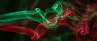 Abstract red and green smoke swirls creating dynamic flowing patterns against dark background for creative design projects and artistic compositions.