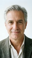 Mature man with gray hair wearing casual business attire, smiling at camera against white background. Suitable for corporate, professional, and lifestyle marketing materials.