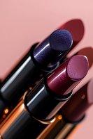 Luxurious metallic lipsticks in deep purple and burgundy shades with shimmer effect on pink background, macro photography showing texture and shine details.