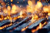 Glowing hot charcoal and flames with sparks flying in dark background, macro shot of burning embers creating atmospheric mood for grilling and barbecue concepts.