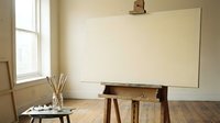 Empty artist easel with blank canvas in bright studio room with wooden floor and natural window light for creative painting workspace.