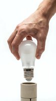 Senior man hand placing LED light bulb into socket on white background isolated for energy saving and innovation concepts.