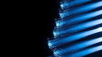Blue fiber optic cables with glowing light streaks on black background for technology and communication concepts.