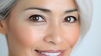 Young Asian woman with silver hair and brown eyes smiling warmly at camera showing natural beauty and confidence for skincare and wellness concepts.