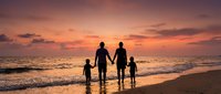 Family of four walking hand in hand on beach at sunset with golden sky and ocean waves creating peaceful vacation moment for travel and togetherness concepts.
