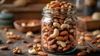 Mixed nuts in glass jar on wooden table with scattered almonds cashews walnuts hazelnuts for healthy snacking and cooking ingredients.