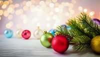 Festive Christmas ornaments and pine branches on wooden surface with soft bokeh lights background for holiday decorations.