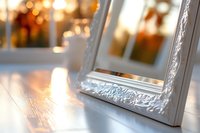 Elegant white ornate frame corner with soft bokeh background and warm glowing candlelight reflections on glossy surface creates romantic atmosphere.