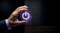 Male hand holding glowing purple power button symbol against dark background. Represents energy, technology, startup, and digital control concepts for business and innovation designs.