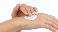 Female hands applying white cream or lotion to skin for skincare, cosmetics, beauty treatment, moisturizer product demonstration on white background.