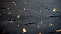 Dark textured surface with glowing golden particles scattered across, creating mysterious atmospheric effect against black background. For luxury branding.
