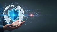 Hand holding holographic globe with blue security shield symbol representing global cybersecurity protection and digital network safety solutions.