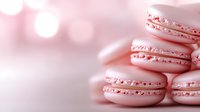 Pink macarons with delicate cream filling stacked against blurred bokeh background, soft pastel tones create dreamy romantic mood for food photography.