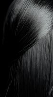 Close-up macro shot of straight black hair strands with silky texture against dark background, creating dramatic contrast and highlighting individual fibers.
