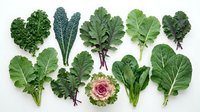 Fresh leafy greens collection featuring kale, collards, bok choy and ornamental cabbage arranged on white background for healthy cooking and nutrition.