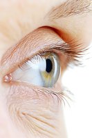 Close-up macro shot of light blue human eye with long eyelashes and detailed iris pattern showing delicate skin texture around eye area. For medical or beauty concepts.