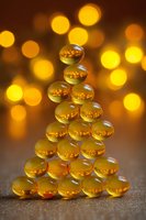 Golden transparent marbles arranged in Christmas tree shape against warm bokeh background, creating festive holiday atmosphere.