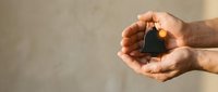 Protective hands cupping small house model symbolizing home insurance, real estate investment, property protection and mortgage security concept.