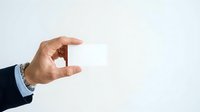 Businessman hand holding blank white card against neutral background for corporate branding and business card mockup presentations.