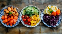 Fresh colorful ingredients in vintage porcelain plates on rustic wooden table, including chicken pieces, vegetables, and citrus slices arranged in rainbow order.