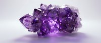 Purple amethyst crystal cluster with vibrant violet gemstone formations on clean white background, isolated for jewelry design and healing concepts.