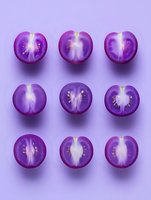 Purple tomato halves arranged in neat rows on lavender background, showing vibrant cross-sections with seeds and flesh patterns creating geometric composition.