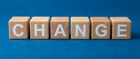 Wooden letter blocks spelling CHANGE on blue background for business transformation and personal development concepts.