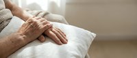 Senior woman hands resting on white pillow in peaceful bedroom setting. Elderly care, comfort, relaxation and aging gracefully concept for healthcare design.