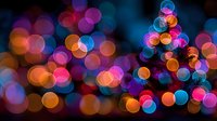 Colorful bokeh lights background with vibrant pink, blue, orange and purple circles creating dreamy festive atmosphere for holiday celebrations and events.