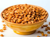 Butterscotch baking chips in yellow ceramic bowl against white background, close up view of sweet cooking ingredients for desserts and confectionery.