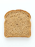 Slice of whole wheat bread with golden-brown crust and airy crumb structure, isolated on white background. Suitable for food packaging, bakery marketing, and culinary design projects.