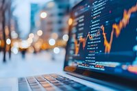Financial market data and stock trading chart on laptop screen with blurred city lights background, showing market analysis and investment trends.