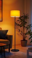 Cozy living room corner with illuminated floor lamp casting warm glow, houseplant and modern armchair creating intimate evening atmosphere for relaxation.