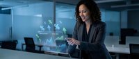 Young woman with long curly dark hair and olive complexion, wearing professional dark blazer, interacting with holographic financial data display showing charts and percentage symbols in modern office environment.