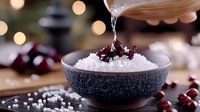 Steaming white rice in ceramic bowl with soy sauce being poured, fresh cherries scattered around, bokeh lights in background creating cozy dining atmosphere.