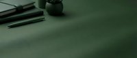 Professional makeup brushes set on green surface with soft shadows creating elegant beauty and cosmetics composition for skincare and fashion applications.
