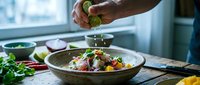 Hands of male chef garnishing fresh vegetable salad with herbs in modern kitchen, food preparation and culinary arts concept for restaurants and cooking content.